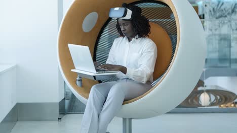 Serious-businesswoman-with-laptop-and-vr-headset